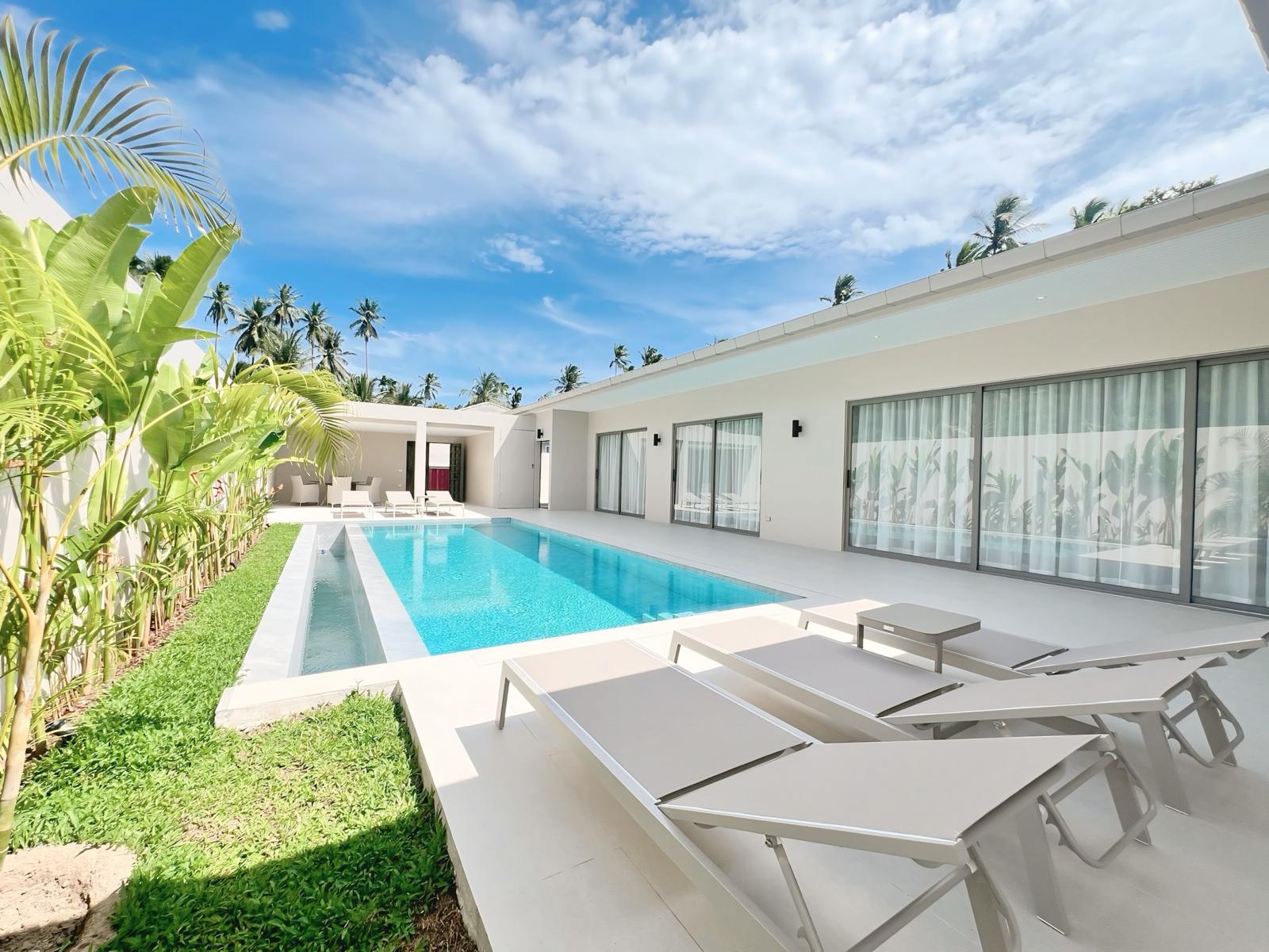 Villa Tropical Golf — façade blanche, longue piscine et cocotiers